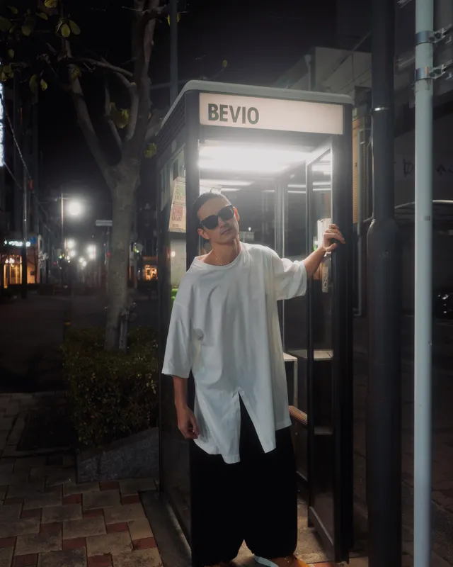 Mettā Atom standing beside a glowing "BEVIO" phone booth at night